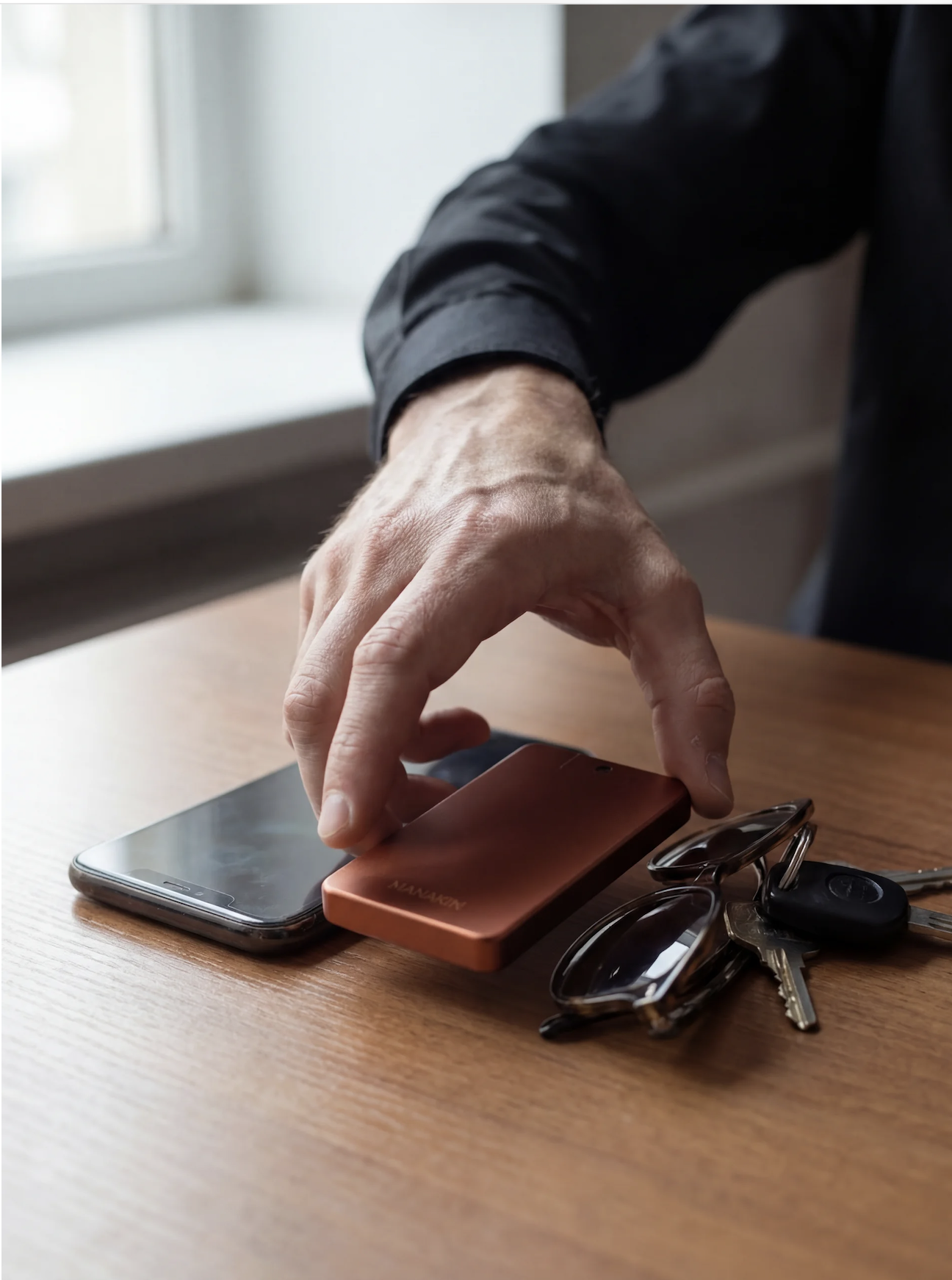 MAN(AKIN) copper device on a desk with phone, keys, and sunglasses